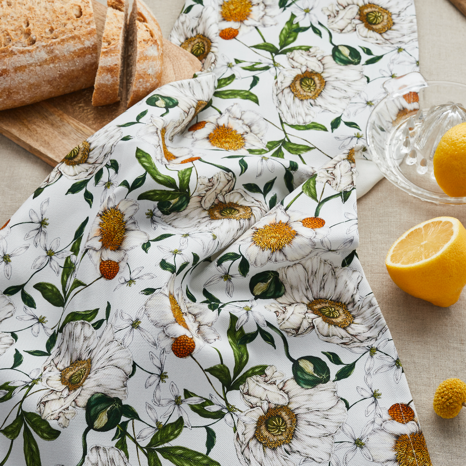 Floral-patterned cloth with lemons and bread on a table