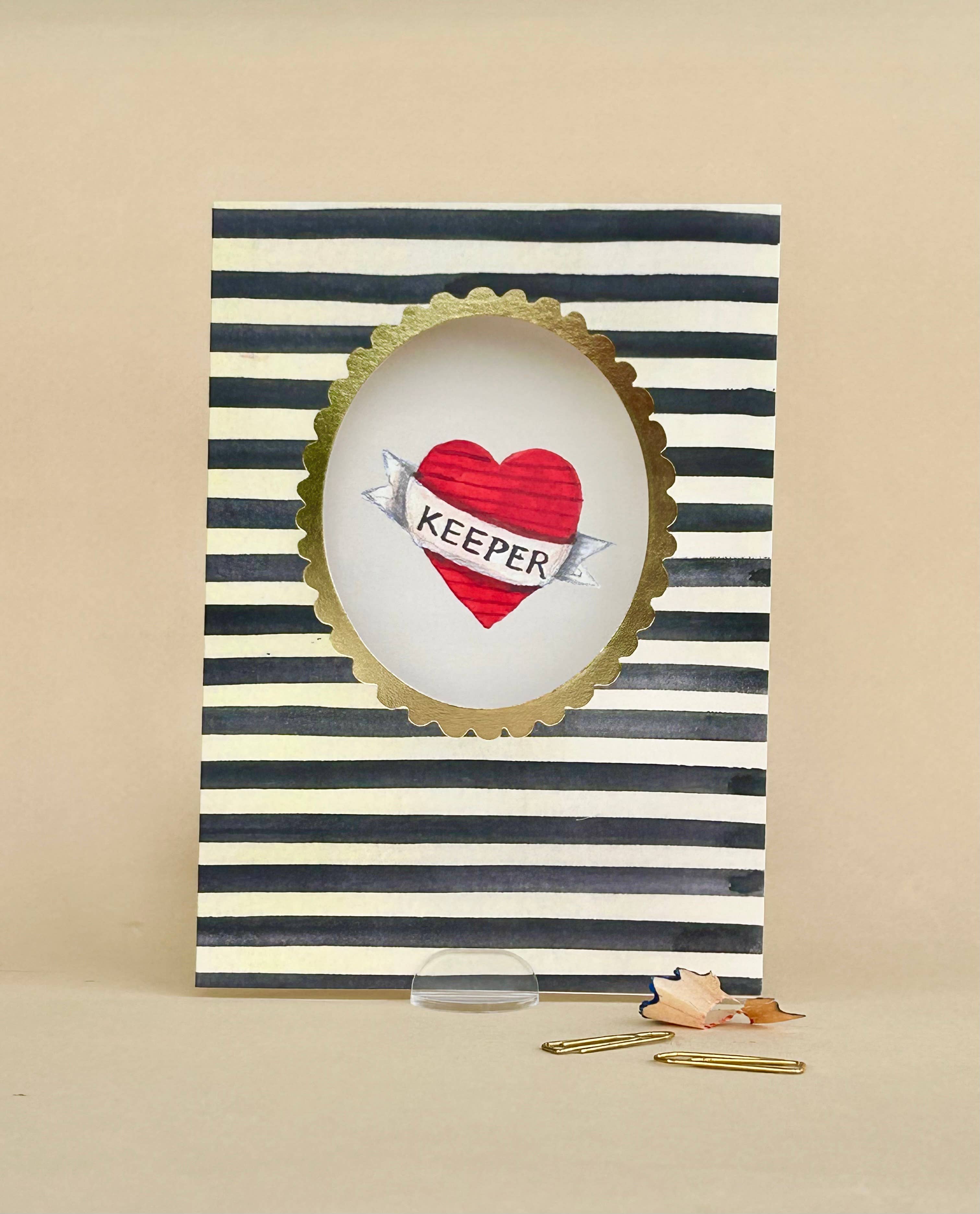 Card with striped border, heart design, and 'KEEPER' text on a beige background