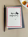 Card with 'Ageing disgracefully' text and a pen on a beige surface