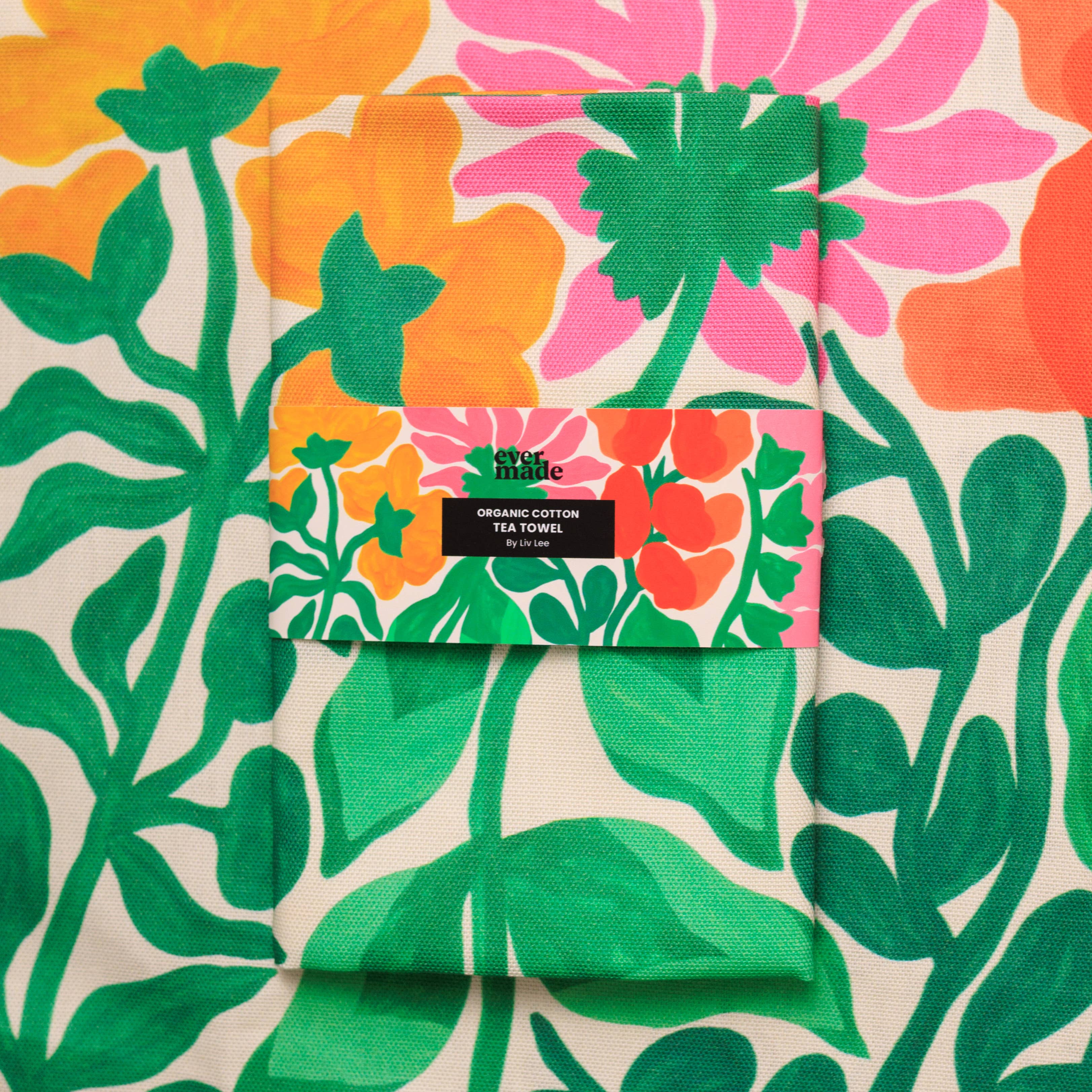 Floral patterned tea towel with a brand label on a matching fabric background