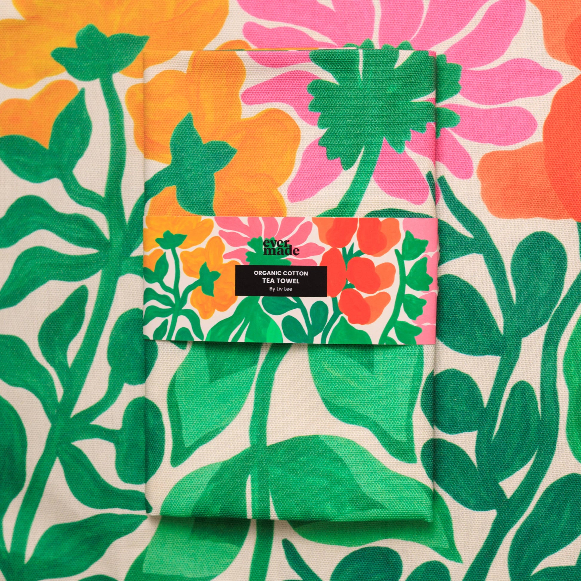 Floral patterned tea towel with a brand label on a matching fabric background