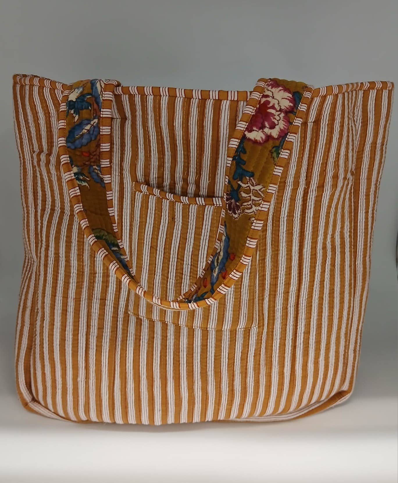 Striped tote bag with floral accents on a plain background