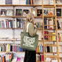 Person holding a tote bag with a message in a bookstore