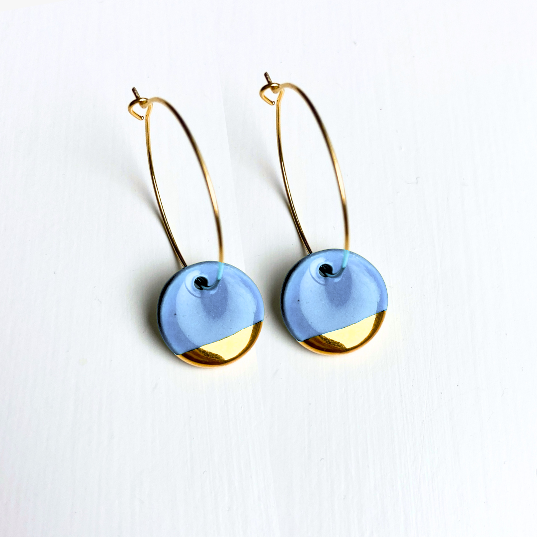 Pair of earrings with gold and blue circular design on a white background