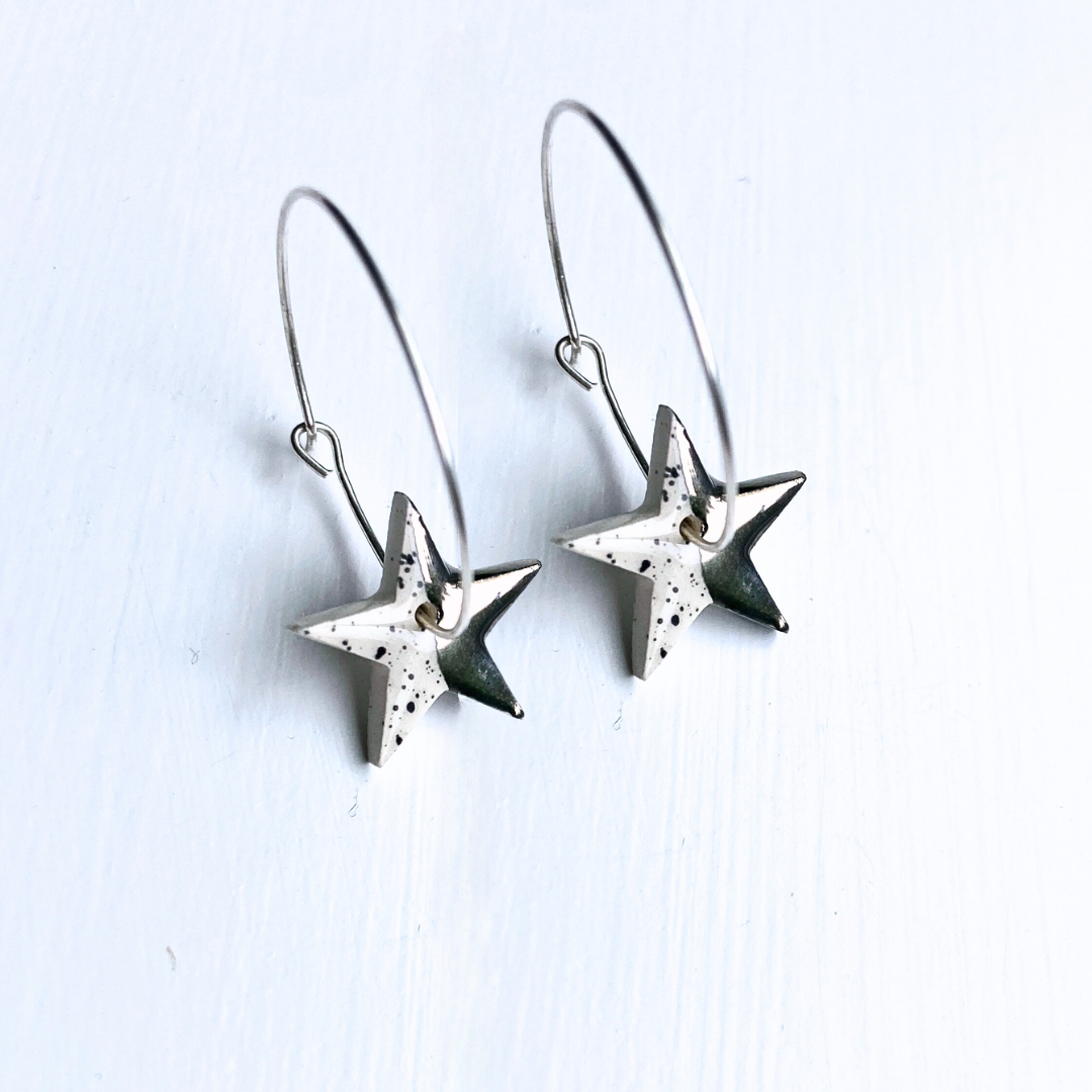 Star-shaped silver earrings on a light gray background