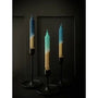 Three gradient candles in black candle holders on a dark background