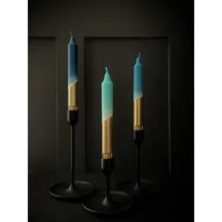Three gradient candles in black candle holders on a dark background