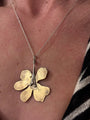 Gold flower-shaped pendant on a chain worn around the neck.