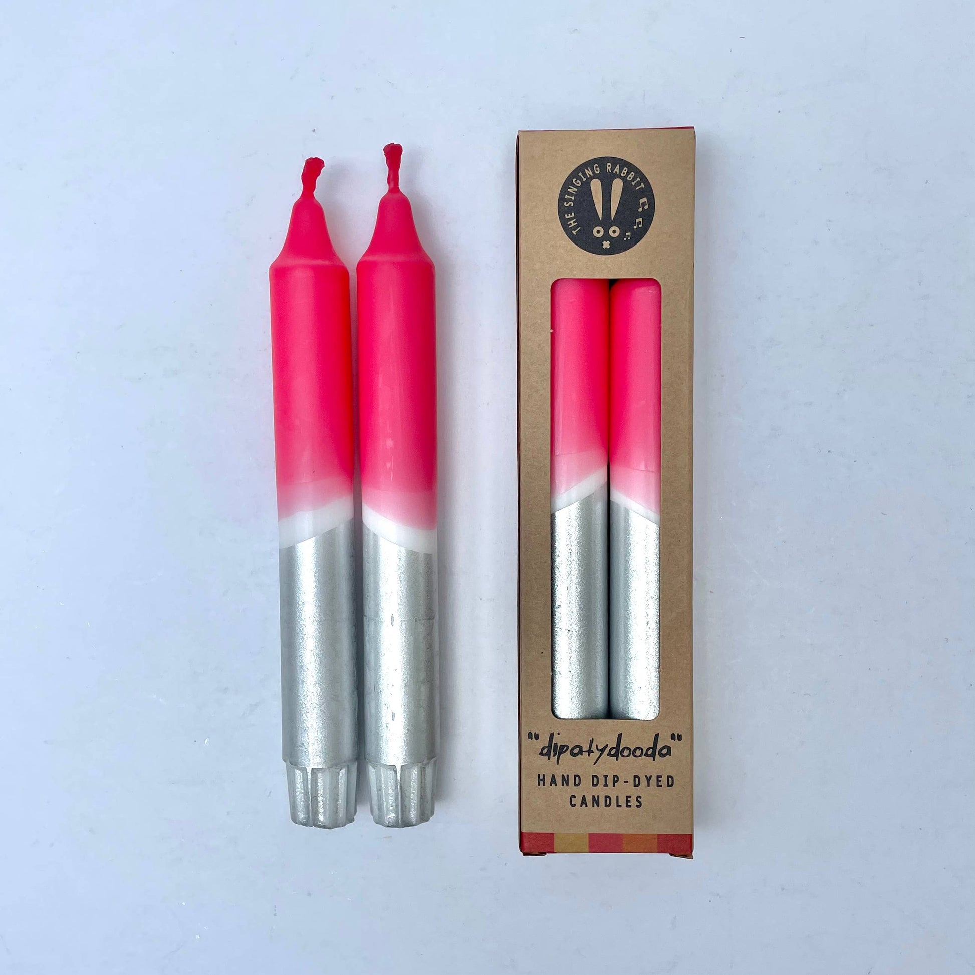 Two pink and silver candles with a cardboard packaging box on a white background