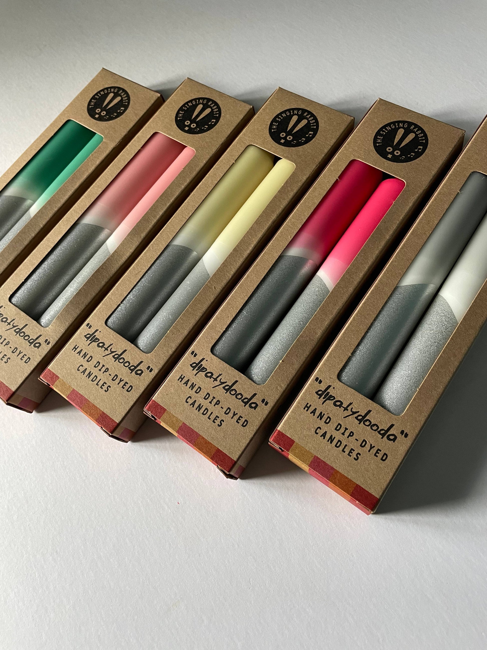 Set of candles in packaging with visible brand name on a light background