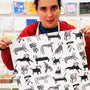 Person holding a large piece of paper with black and white dog illustrations in front of a colorful wall.