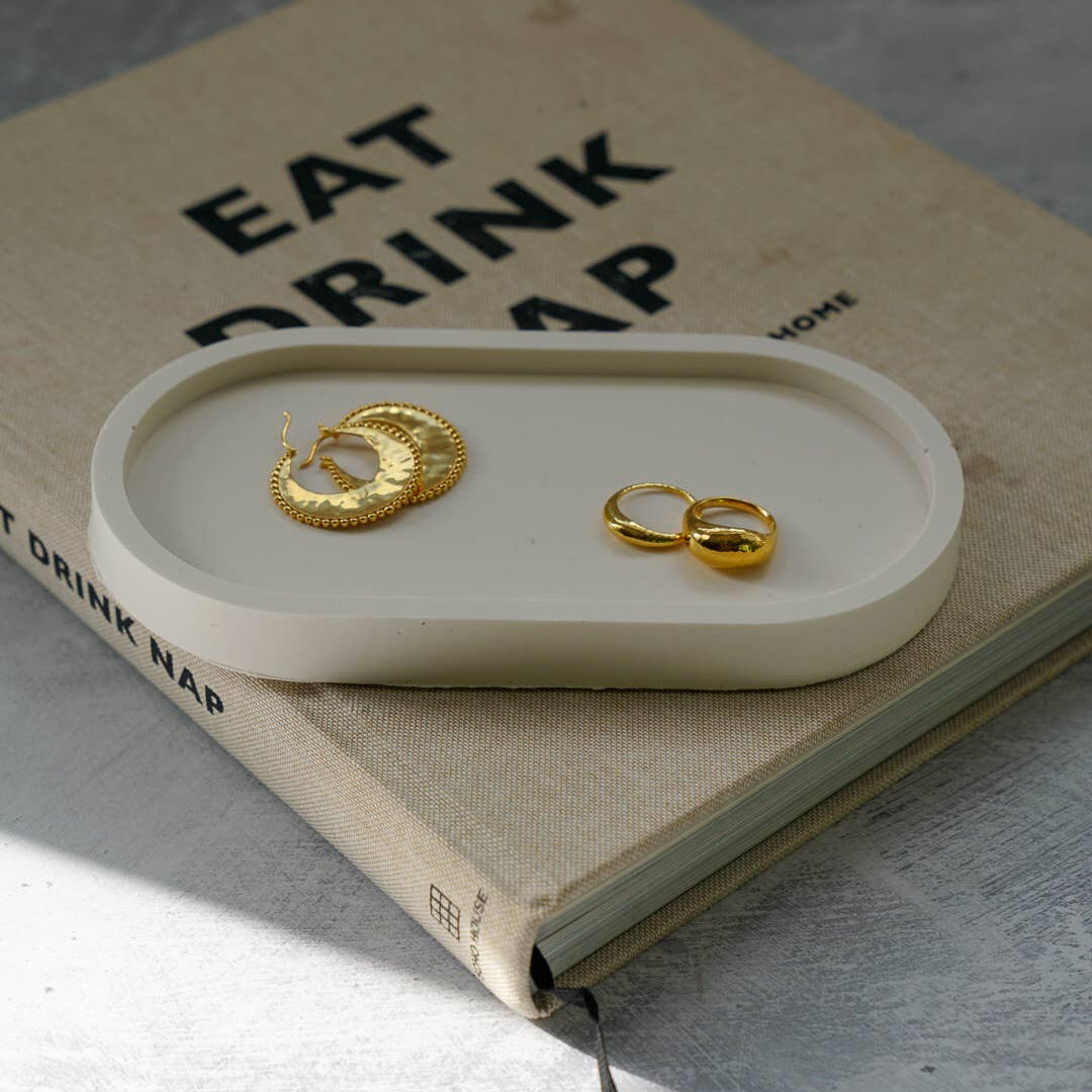 Gold earrings on a white tray with a book underneath