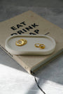 Gold earrings on a white tray with a book underneath