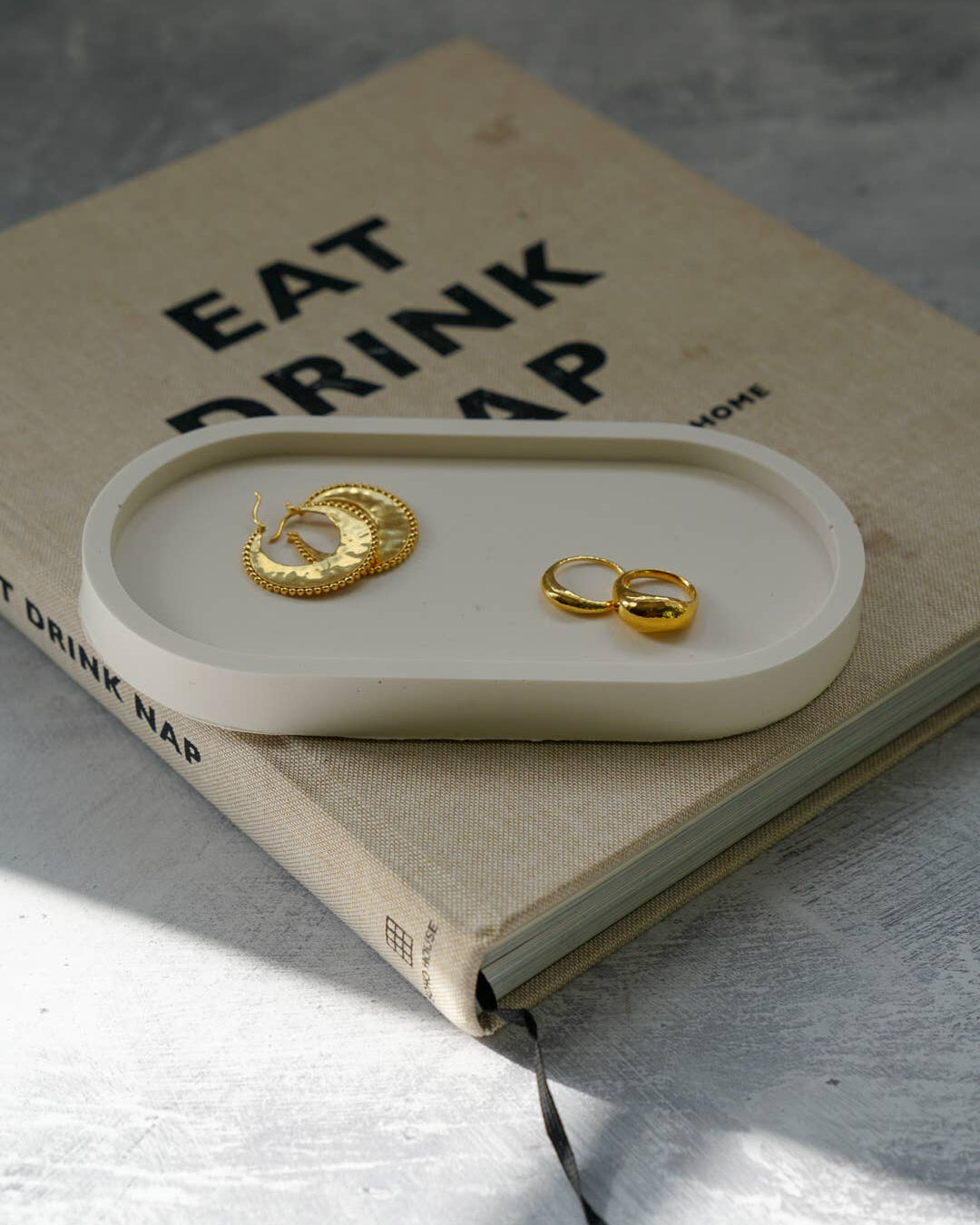 Gold earrings on a white tray with a book underneath