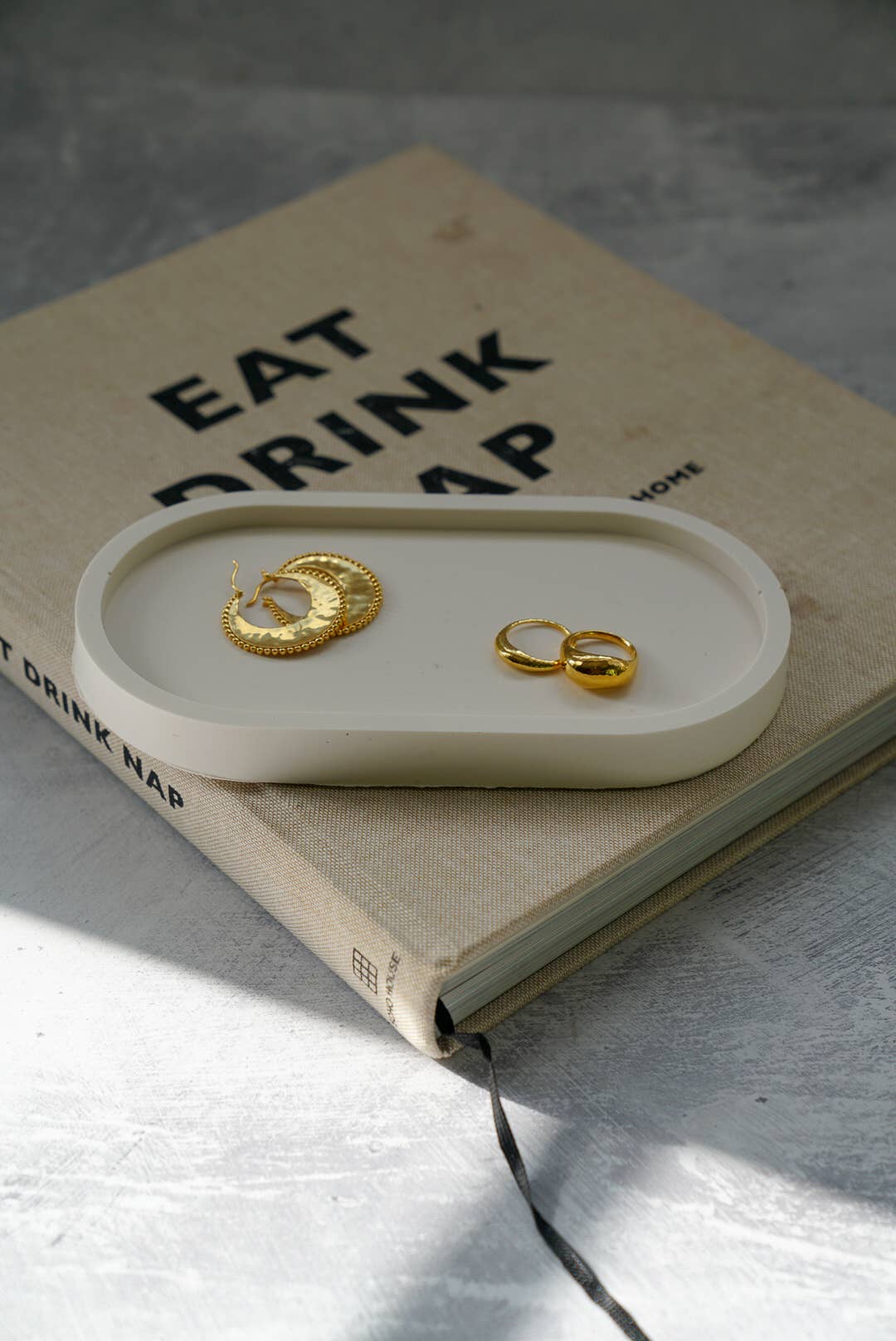 Gold earrings on a white tray with a book underneath