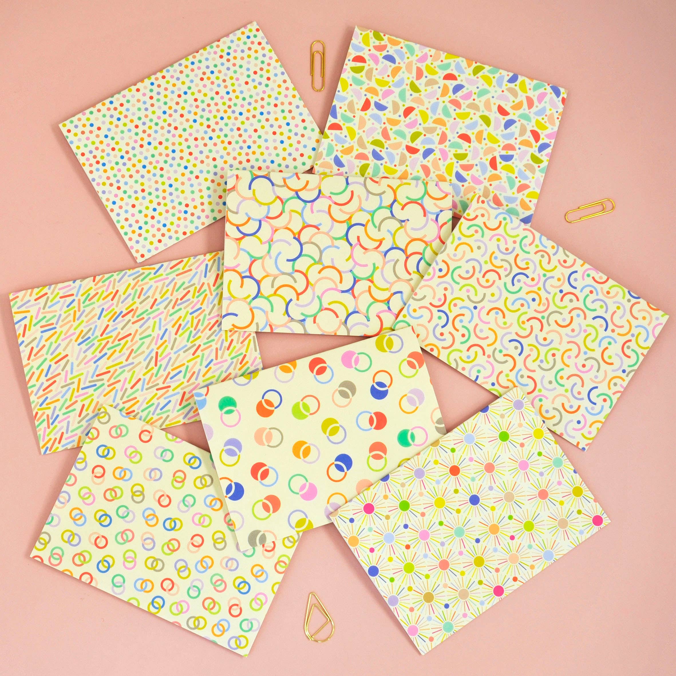 Set of colorful patterned paper sheets on a pink background