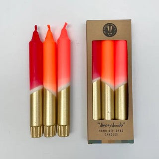 Two gradient candles with a gold base and red top, alongside their packaging box on a light gray background.