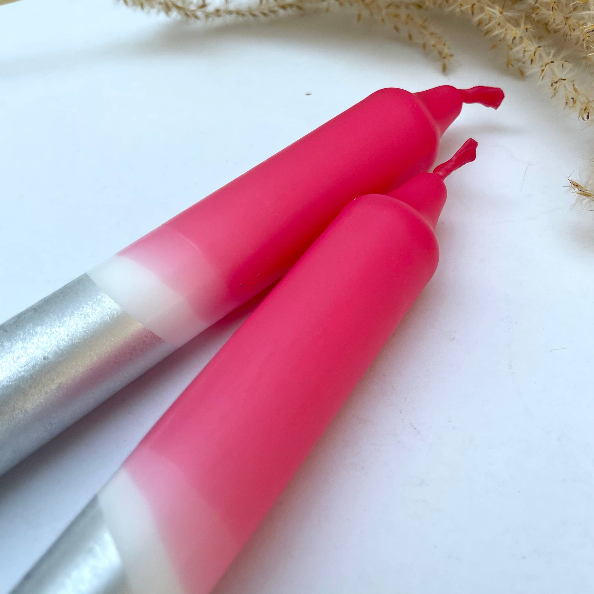 Two pink lip glosses with silver bases on a white background