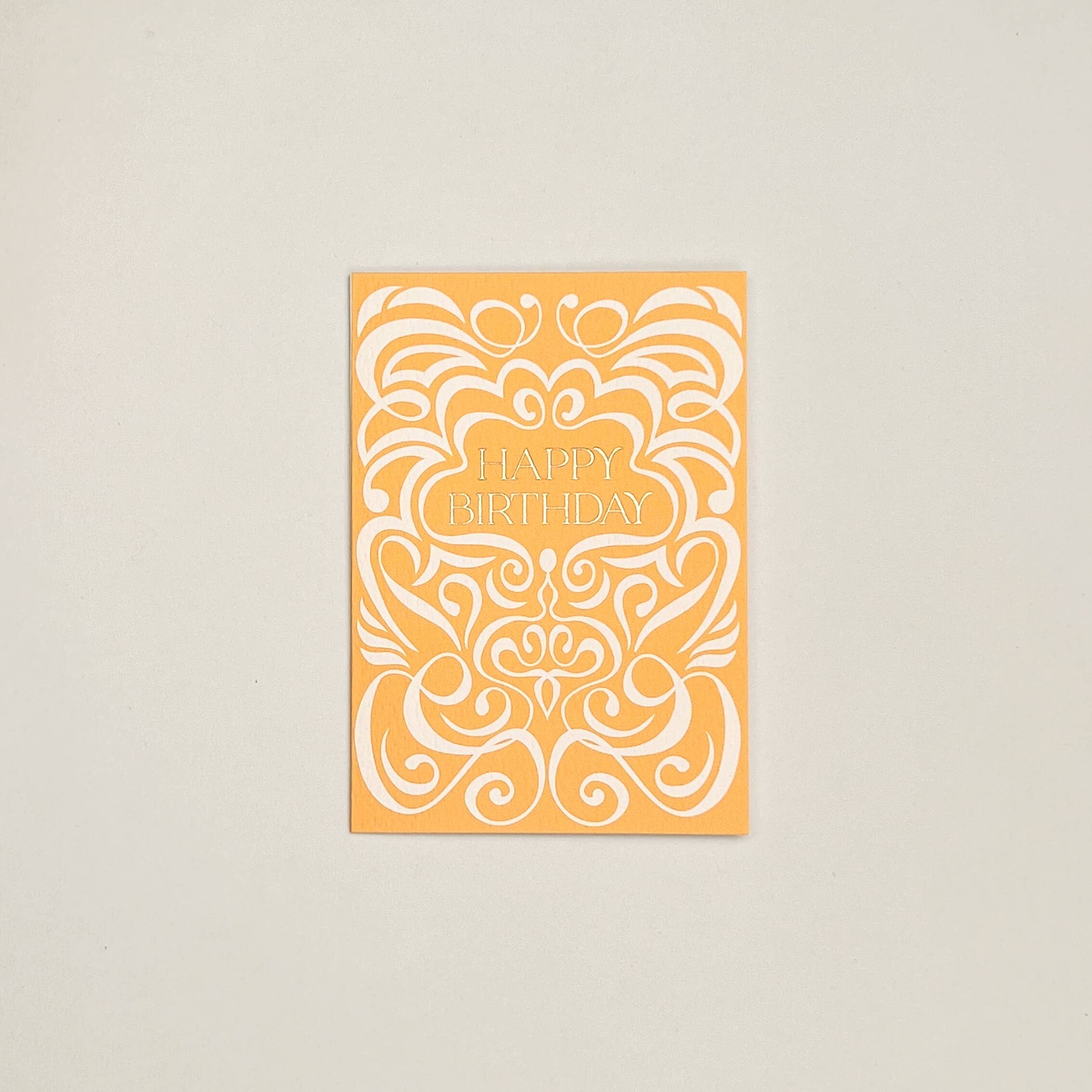 Orange birthday card with white decorative patterns on a beige background