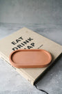 Ceramic tray on a book titled 'Eat Drink Nap' with a gray background