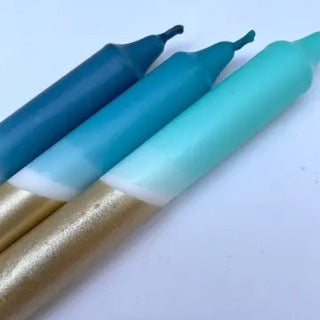 Three markers with blue, green, and gold bodies on a light blue background