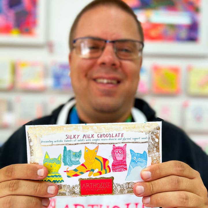 Person holding a bar of silky milk chocolate with colorful packaging featuring animal illustrations.