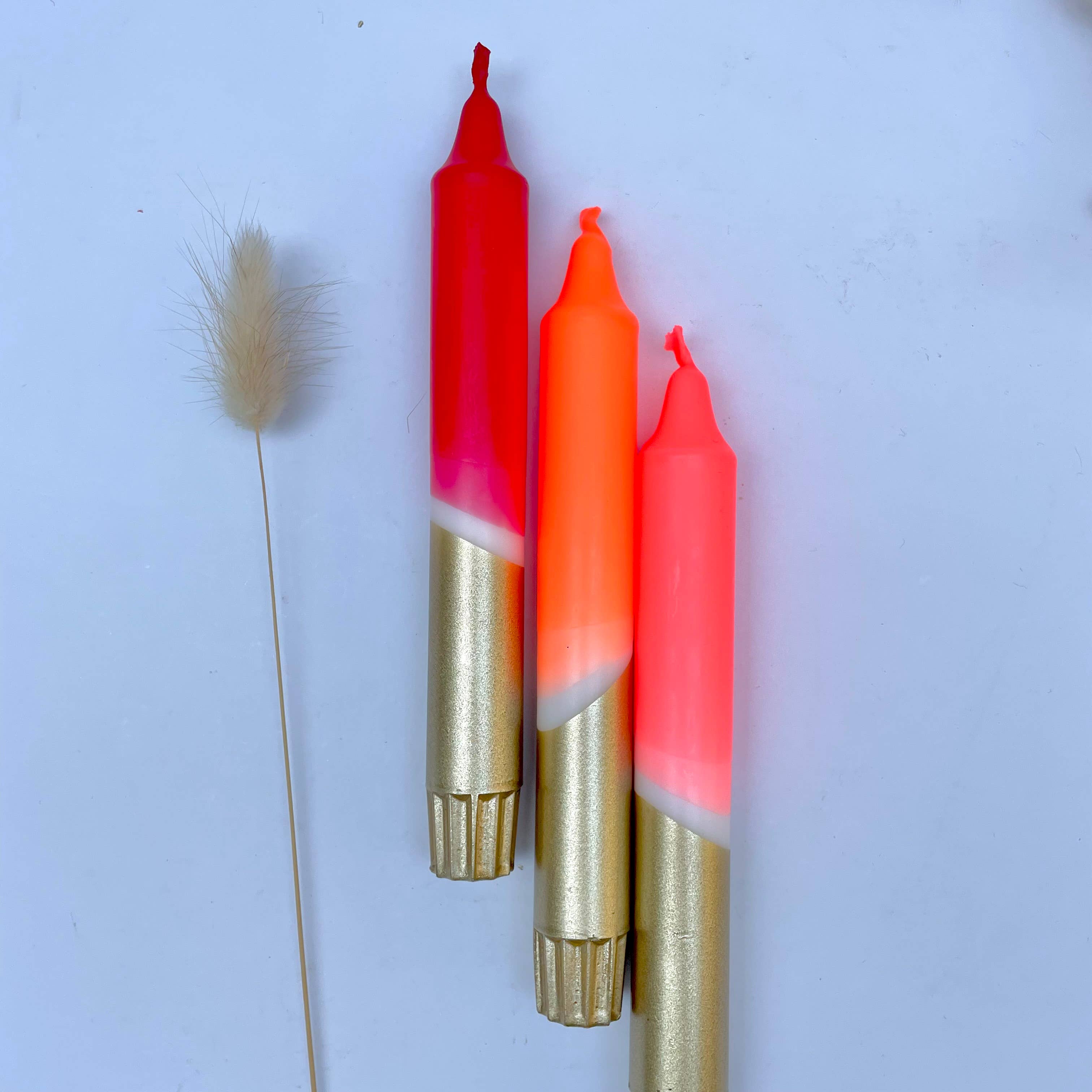 Three lipsticks with gold bases on a light blue background