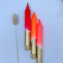 Three lipsticks with gold bases on a light blue background