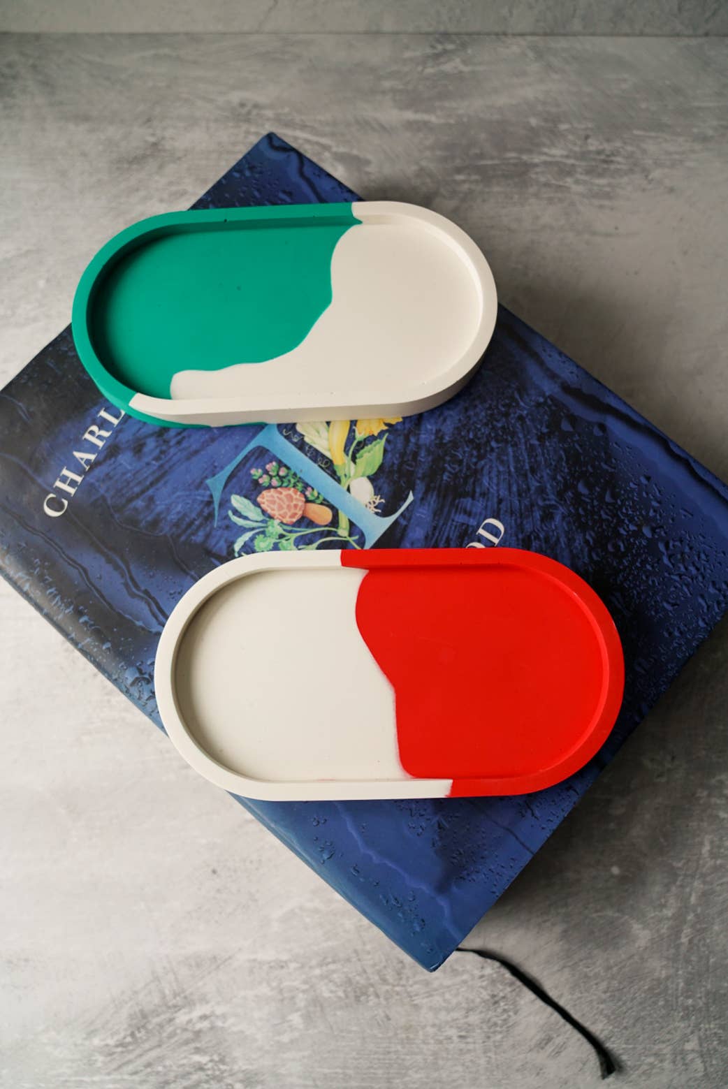 Two colorful containers on a book with a gray background