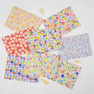 Collection of colorful floral-patterned paper bags on a white background
