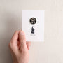 Hand holding a card with a button and text on a plain background