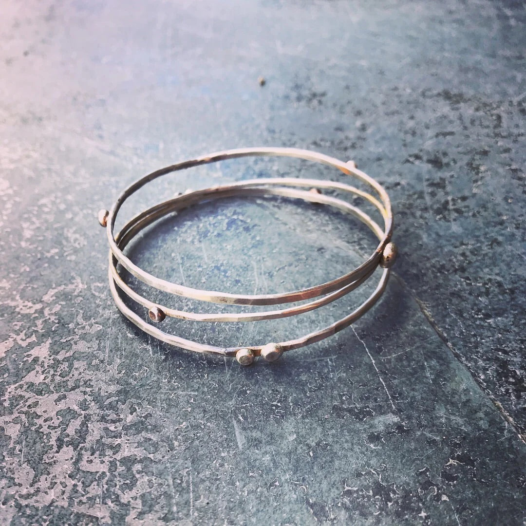 Stack of silver bangles on a textured surface
