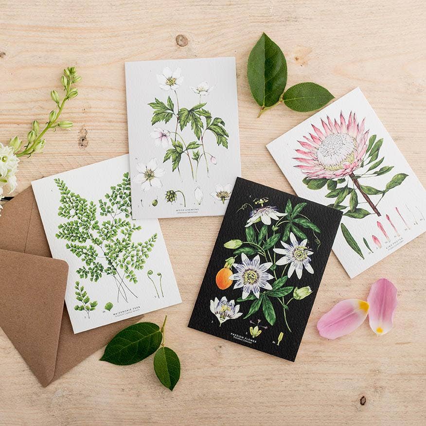 Set of botanical greeting cards on a wooden surface with leaves and flowers.