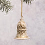 Decorative bell ornament with gold patterns hanging against a light background