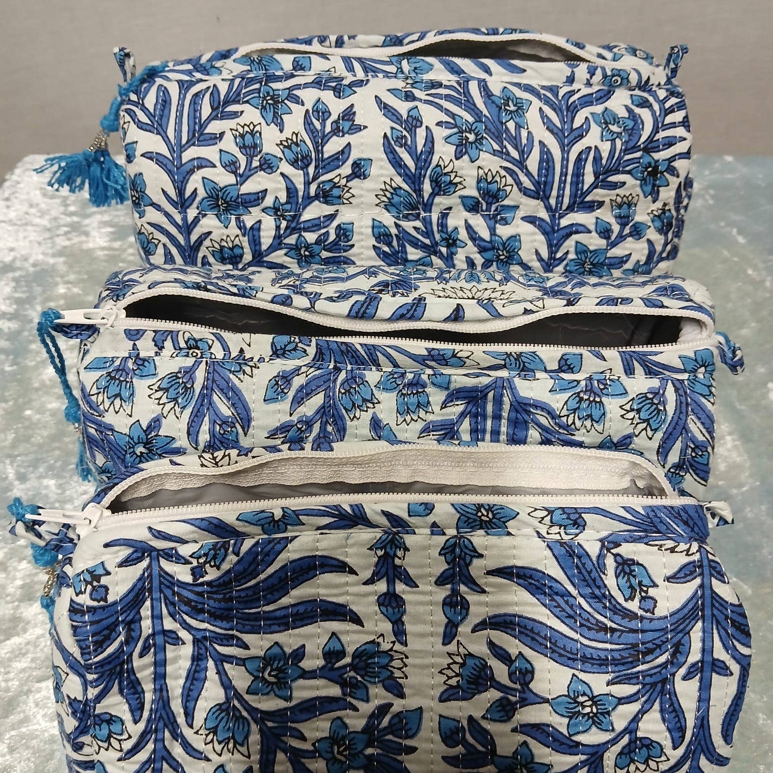 Set of three blue and white floral-patterned bags on a gray surface
