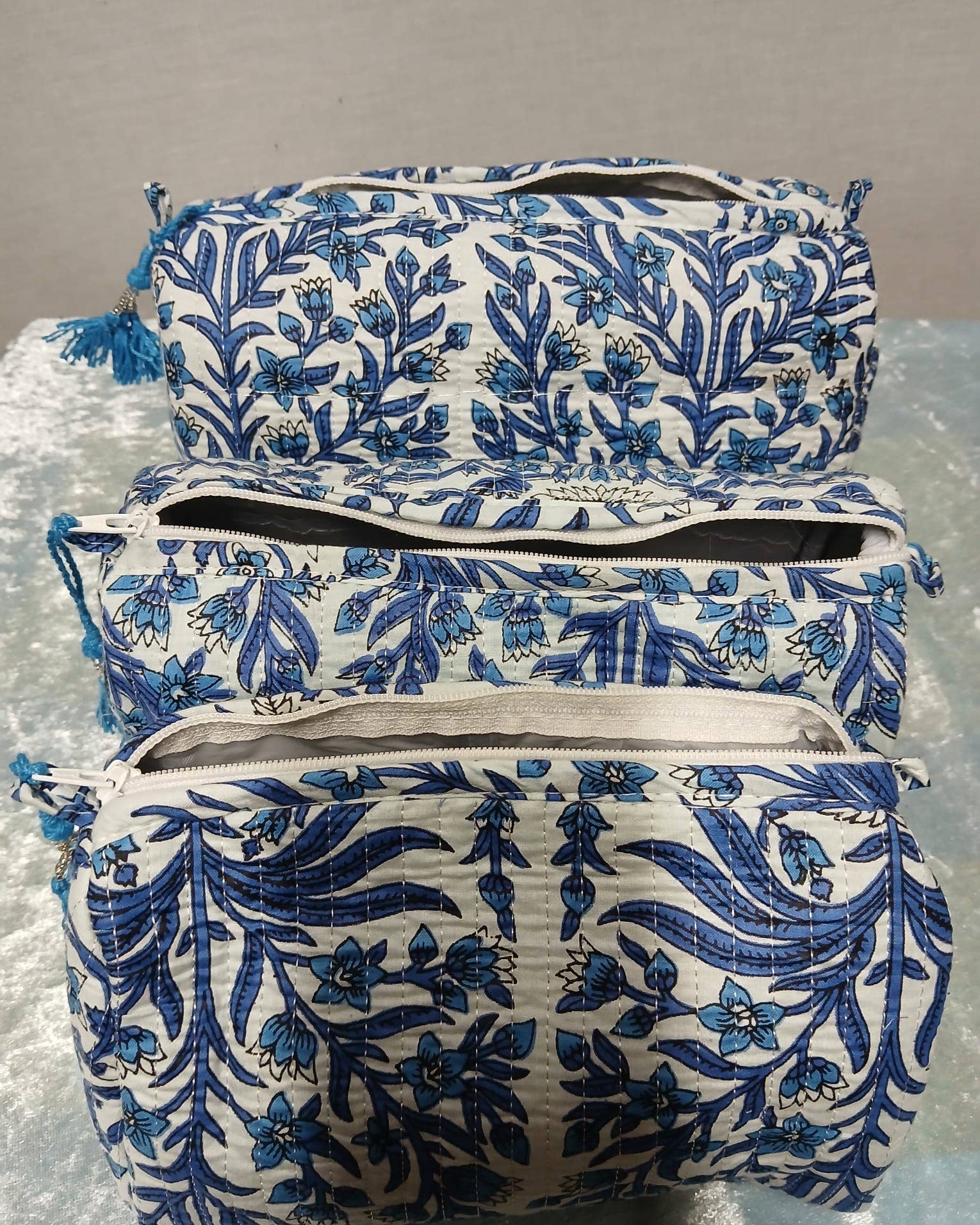 Set of three blue and white floral-patterned bags on a gray surface