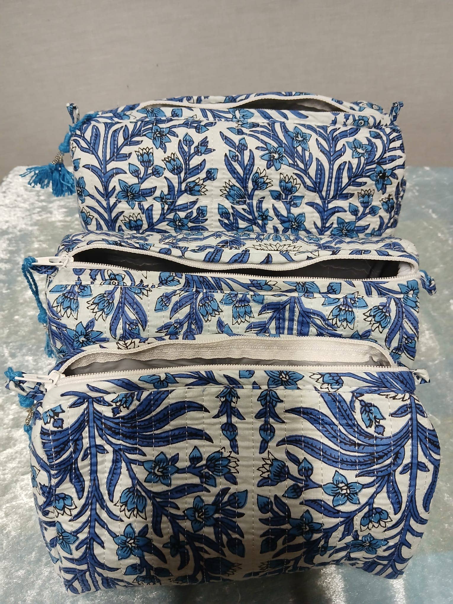 Set of three blue and white floral-patterned bags on a gray surface