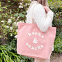 Person holding a pink tote bag with 'books & snacks' text in a garden setting
