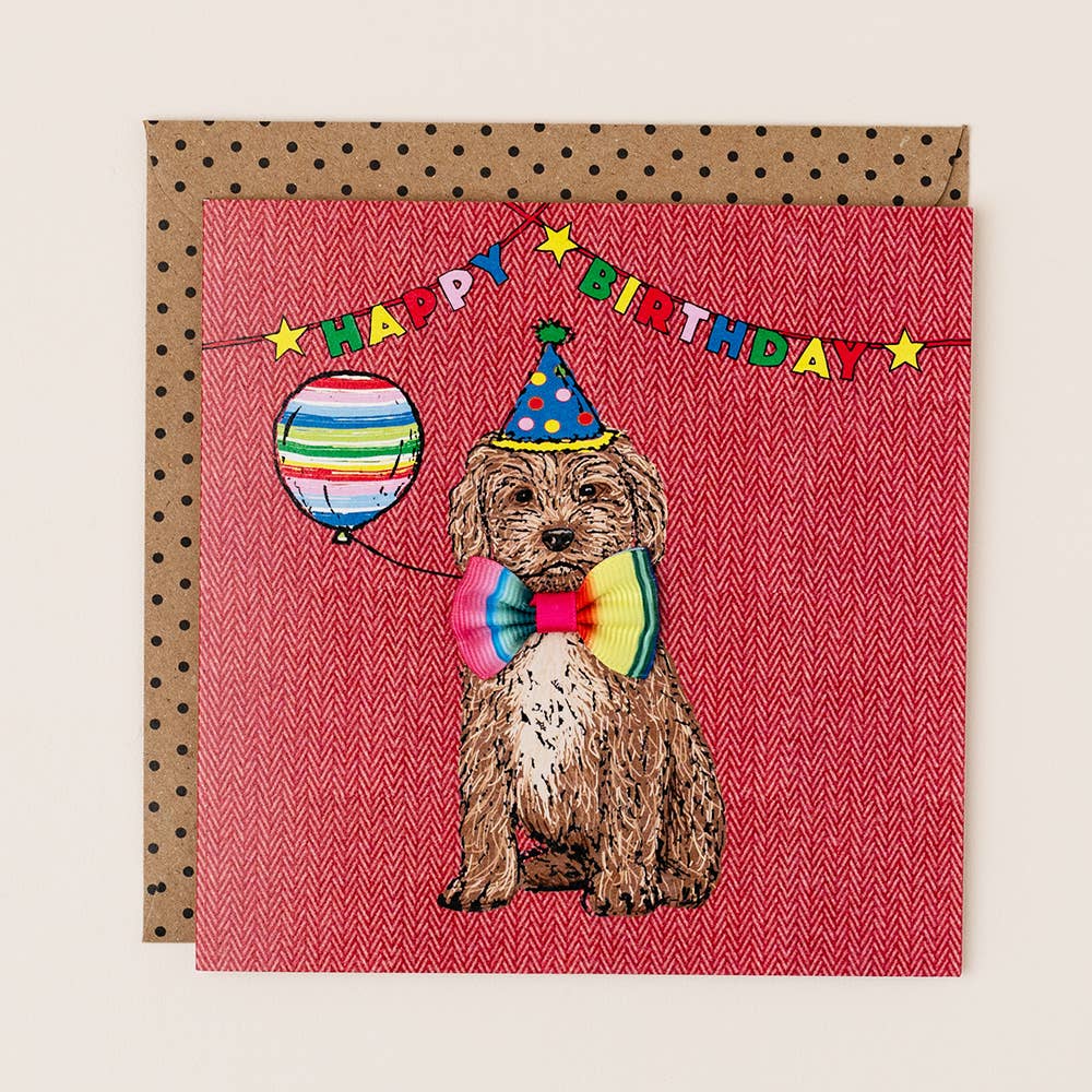 Birthday card with a dog wearing a party hat and bow tie, holding a balloon, on a red background.