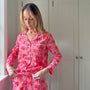 Woman wearing a red floral pajama set standing in a room with white doors.