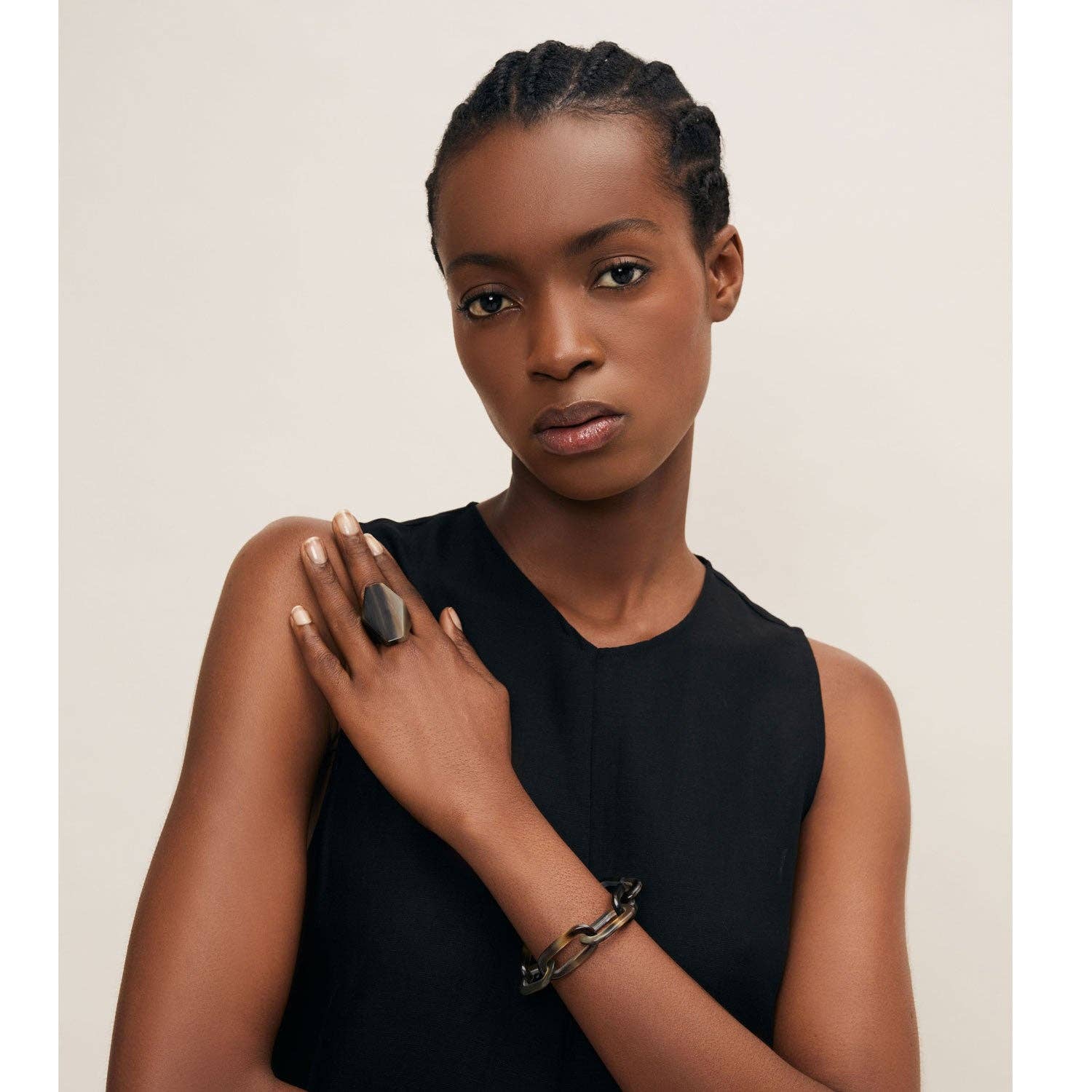 Woman wearing a black sleeveless top with a neutral background