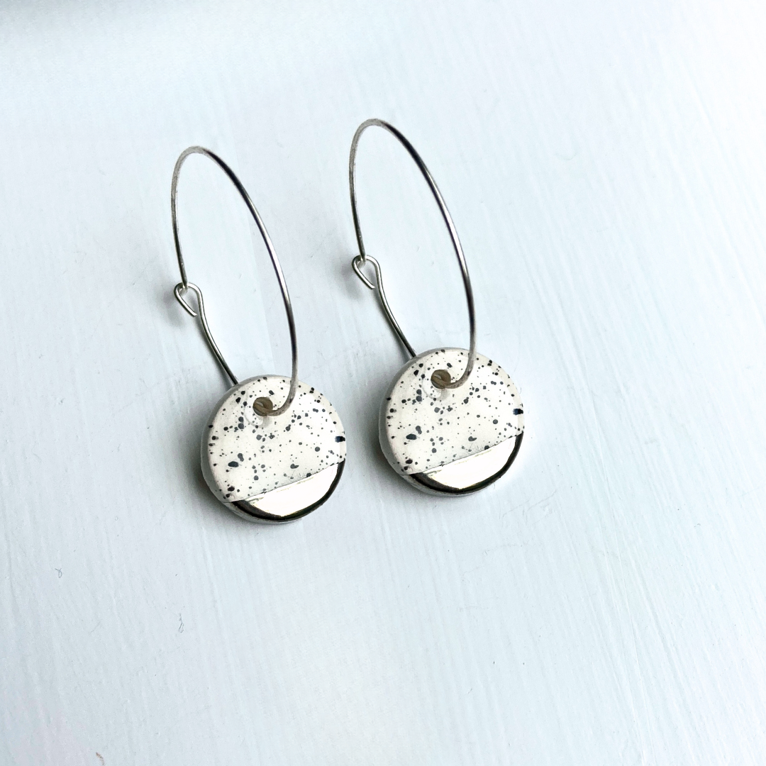 Pair of earrings with speckled circular designs on a light background
