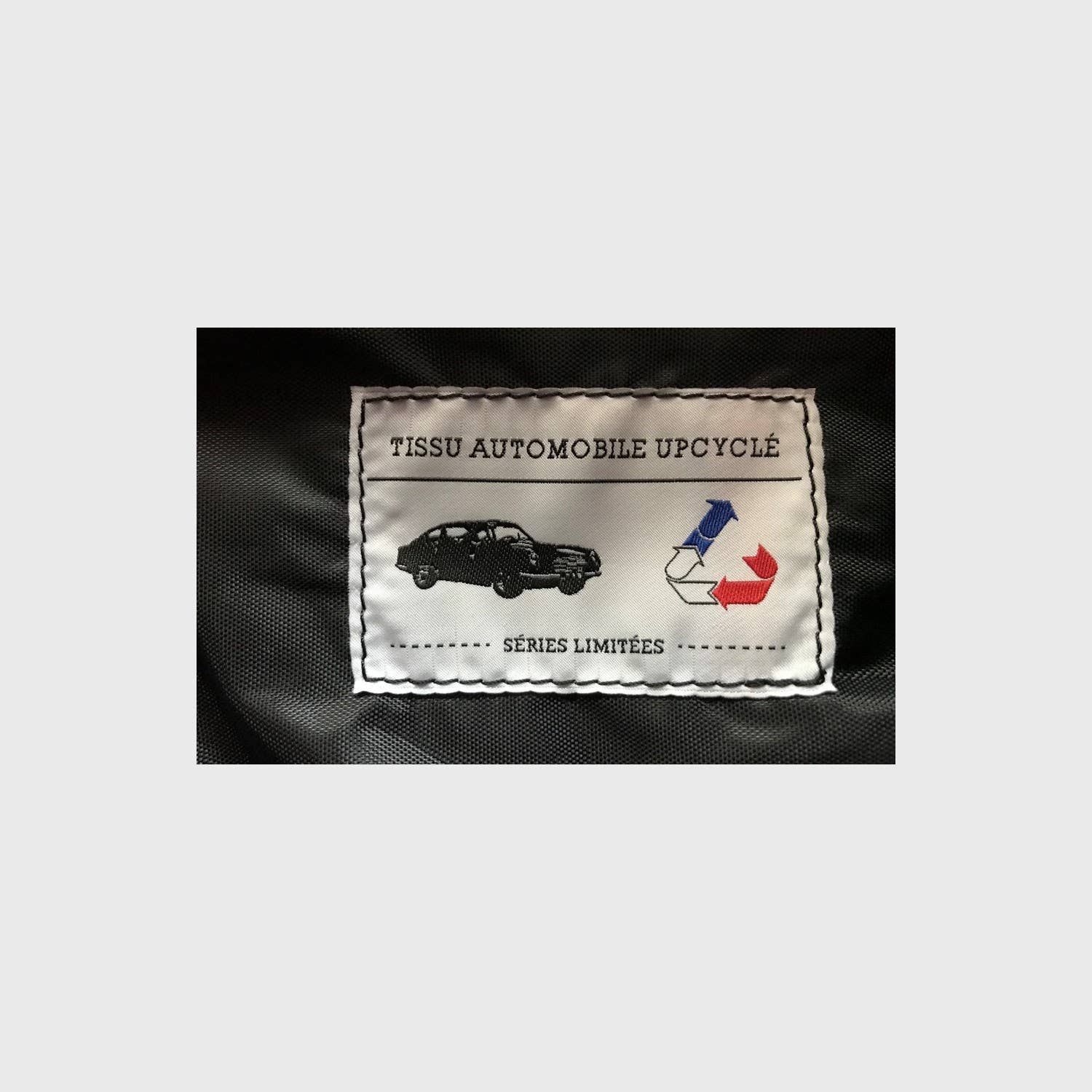 Label on fabric indicating upcycled automotive material with recycling symbol