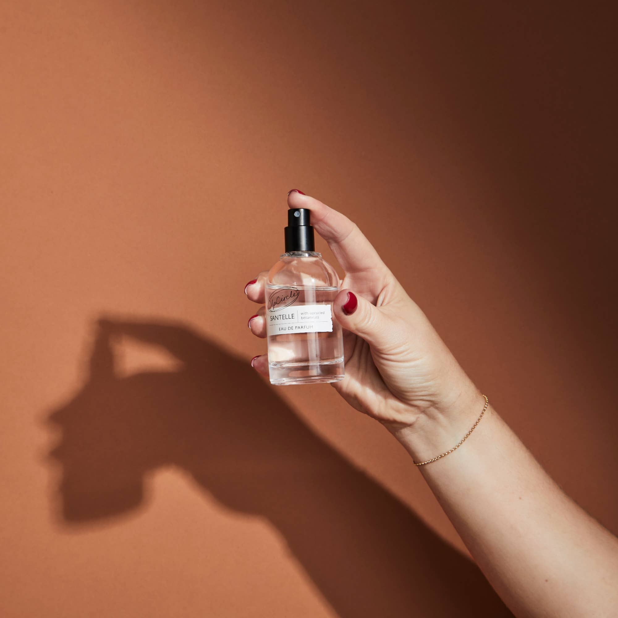 Hand holding a clear bottle with a label against a brown background