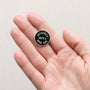 Pin with 'Officially Quite a Good Dad' text held in a hand against a light background