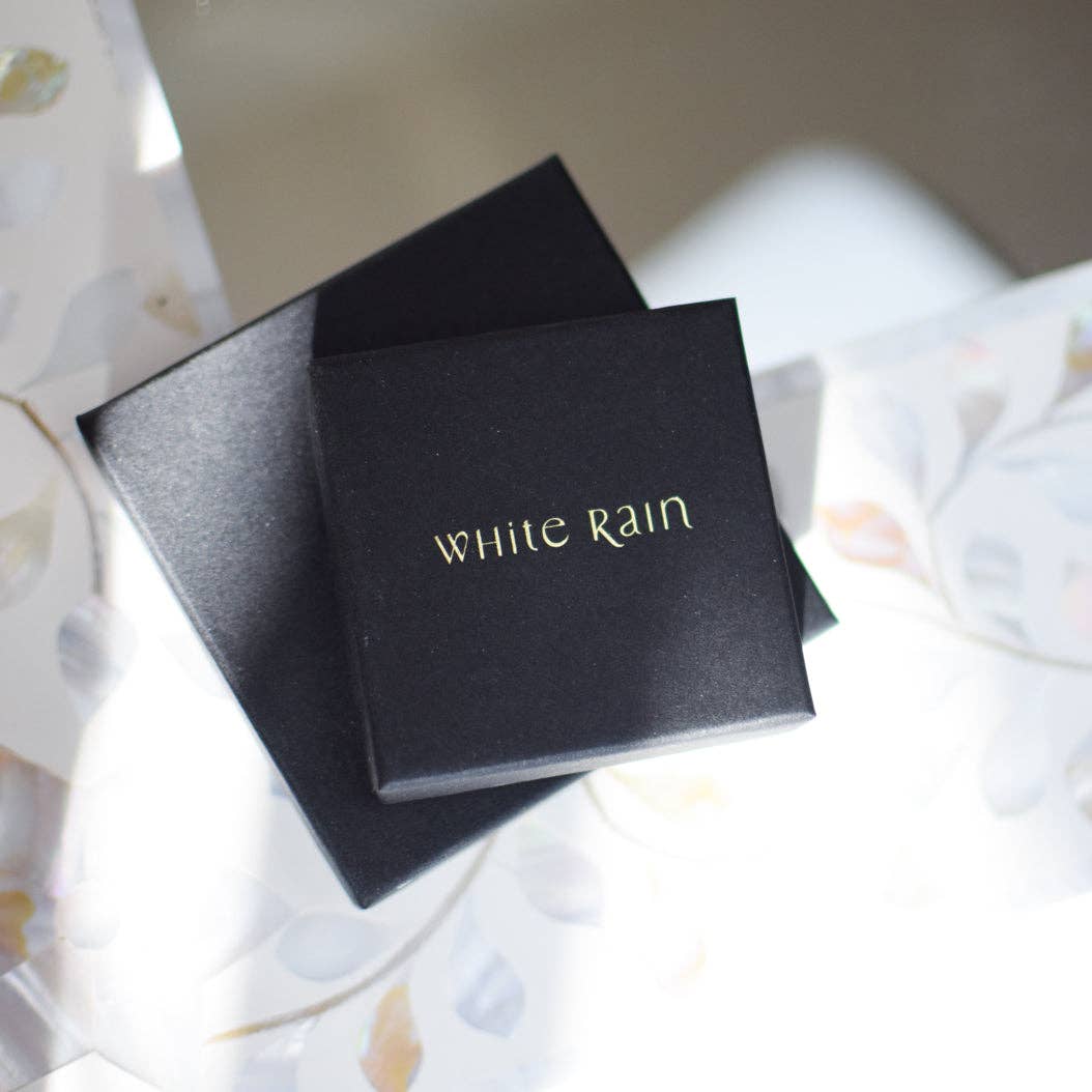 Black box with 'White Rain' branding on a light fabric background