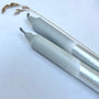 Two metallic pens on a white background with grass-like material.