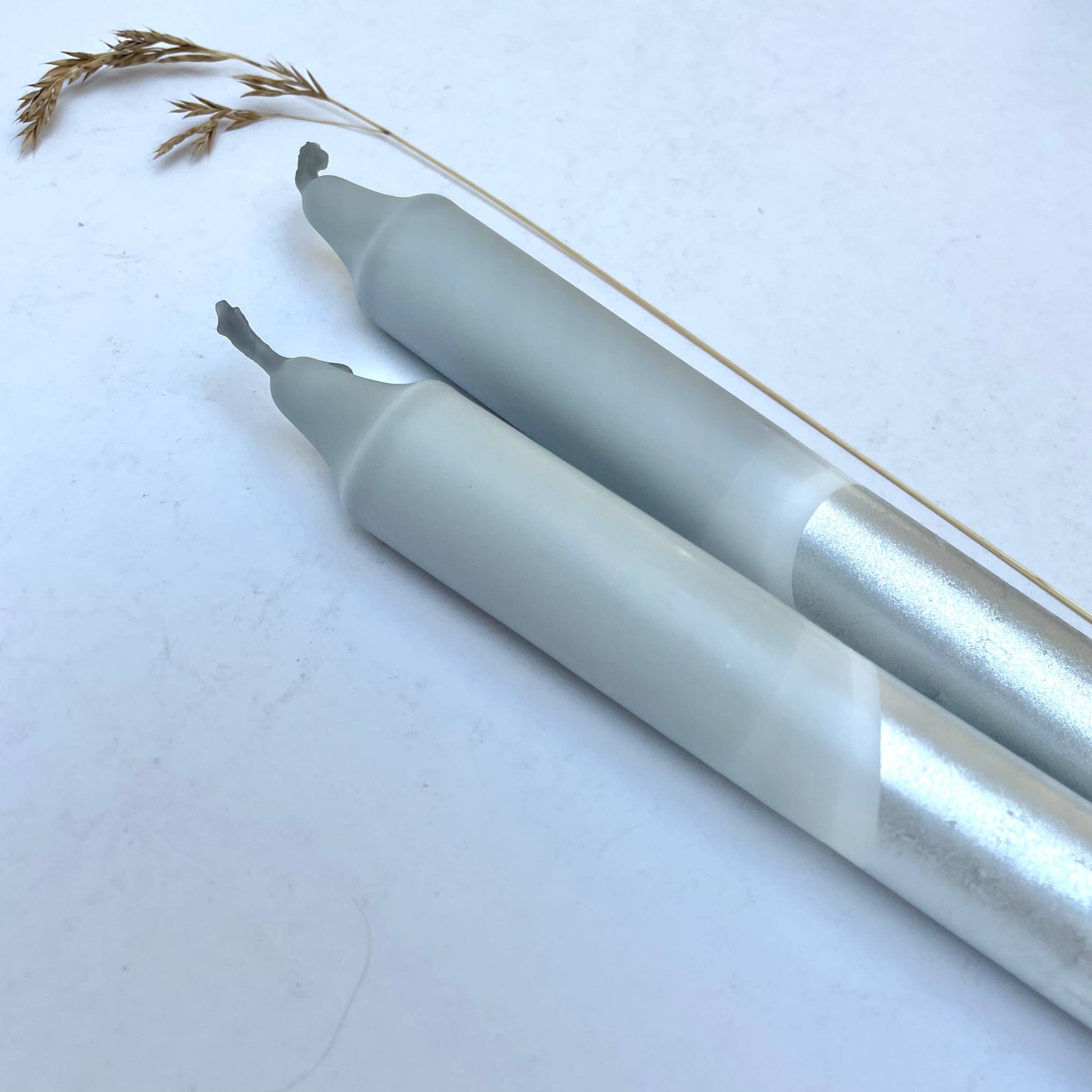Two metallic pens on a white background with grass-like material.