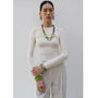 Person wearing a white outfit with green accessories against a gray background