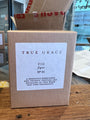 Box of 'True Grace Fig' candle with a label on a wooden surface